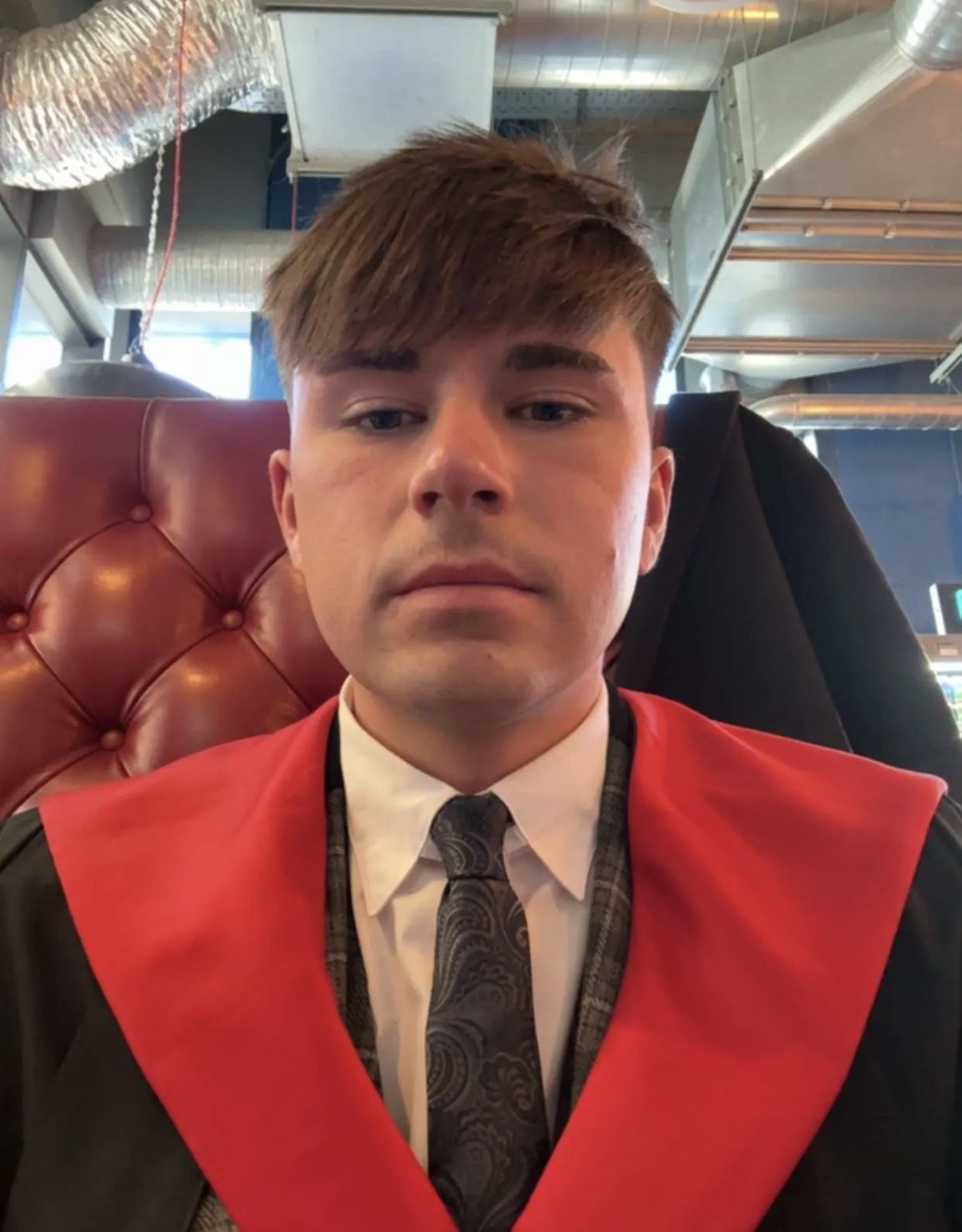 Brent in his graduation gown with a red hood